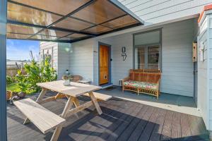 une terrasse avec une table de pique-nique et un banc sur une maison dans l'établissement Ekhaya - New Plymouth Holiday Home, à New Plymouth
