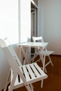 duas cadeiras brancas e uma mesa e uma mesa e cadeiras em Solomon Apartments ap 1 em Sîngeorgiu de Mureş