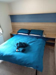 1 cama con sábanas azules y almohadas azules en New 2 bed holiday home with decking in Rockley Park Dorset near the sea, en Lytchett Minster