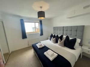 um quarto com uma cama grande e almofadas azuis e brancas em Casa Fresa - City Quay Apartment em Dundee