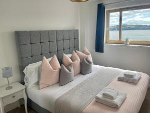 um quarto com uma cama com almofadas cor-de-rosa e uma janela em Casa Fresa - City Quay Apartment em Dundee