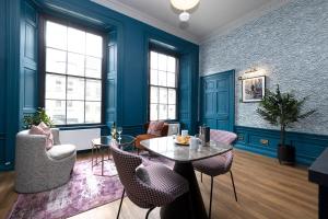 a living room with blue walls and a table and chairs at 30 Castle Street Aparthotel in Edinburgh