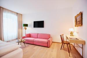 a living room with a pink couch and a table at Boutiquehotel Zum Goldenen Hirschen in Gmunden