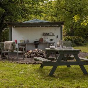 a picnic table in the grass with a kitchen in the background at Duneden Belle Glamping in Randalstown