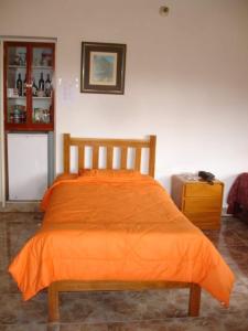 1 cama con edredón naranja en una habitación en Swiss Chalet with Private Kitchen near Lima en Canta