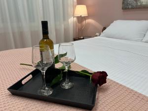 a tray with two glasses and a bottle of wine on a bed at Kavala Port Apartments in Kavála