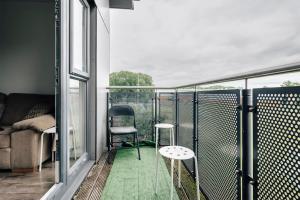 a balcony with a couch and two stools on it at Lloyd St Apartment in Manchester