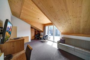 an attic room with a couch and a tv at Hotel Landgasthof Eischen in Appenzell