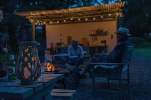 two men sitting in chairs around a fire at night at Duneden Belle Glamping in Randalstown