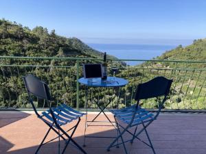 2 sillas y mesa con ordenador portátil en el balcón en AL GEKO DEL GROPPO ☆ Breath & Relax ☆ 5 TERRE, en Volastra