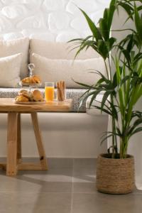 a coffee table with bread and orange juice and a potted plant at Kamvas Deluxe Apartments in Naxos Chora