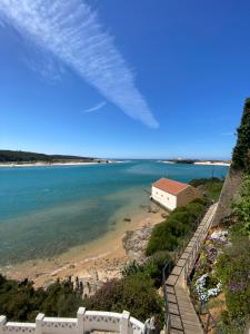 a view of a beach with a house and the ocean at Apartamento Vicentino in Vila Nova de Milfontes
