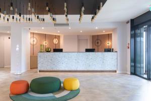 a lobby with colorful chairs in front of a counter at Belstay Milano Linate in Peschiera Borromeo