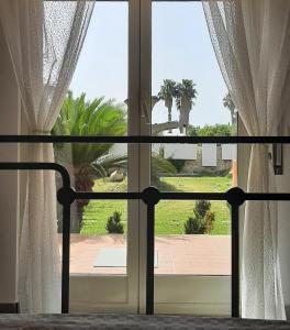 a bedroom window with a view of a garden at Green Rooms - Casa nel verde in Pachino