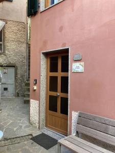 un edificio rosa con una puerta de madera y un banco en AL GEKO DEL GROPPO ☆ Breath & Relax ☆ 5 TERRE, en Volastra