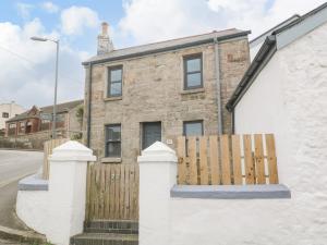 una casa de ladrillo con una valla de madera delante de ella en Rose Bank Cottage en Penzance