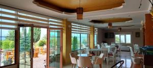 a restaurant with white chairs and tables and windows at HOTEL VILA TOSKA in Piskupat