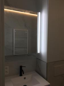 een badkamer met een wastafel en een spiegel bij Studio 4 pers met Frontaal Zeezicht & privé zwembad Oostende in Oostende