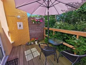 um pátio com uma mesa, cadeiras e um guarda-sol em The Cherry Apartment - 'Den Gule Svane' Guest House near Rønne & Beach em Rønne