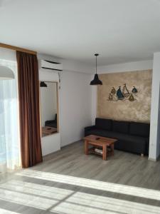 a living room with a black couch and a table at Biandada Apartments in Mamaia Sat/Năvodari