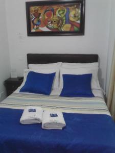 1 cama con 2 almohadas azules y una pintura en la pared en CASA HOTEL VICTORIA Av 30, en Bogotá