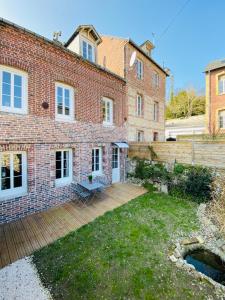 een groot bakstenen huis met een houten terras bij L'Emerald - Etretat in Étretat