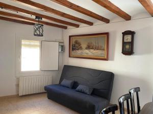 a living room with a blue couch and a clock at Cal cap xic in Castellfullit de Riubregós