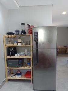 uma cozinha com um frigorífico de aço inoxidável ao lado de uma prateleira em Casa Verde Maré em Pipa