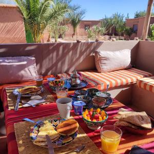 einen Tisch mit Speisen und Getränken auf einer Terrasse in der Unterkunft Maison d'hôtes Tigminou - Adults Only in Aït-Ben-Haddou