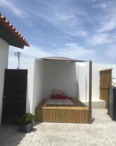 a patio with a bed with an umbrella on it at Moradia Bispo in Aljubarrota