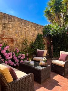 een patio met rieten stoelen, een tafel en bloemen bij Casa Mundet Sant Antoni de Calonge in Sant Antoni de Calonge