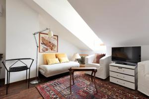 a living room with a white couch and a tv at Bellagio Retreat lake view apartment in Limonta