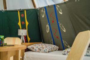 ザトルにあるWioska Indiańska River Parkのテント付きの客室で、ベッド1台とテーブルが備わります。