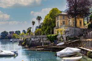 two boats in the water in front of a building at Bellagio Retreat lake view apartment in Limonta