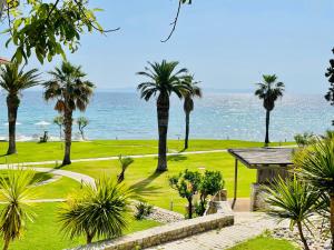 - une vue sur un parcours de golf avec des palmiers et l'océan dans l'établissement Afitis Boutique Hotel, à Afytos