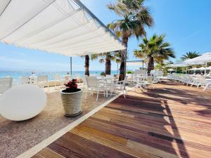 a patio with white tables and chairs and the beach at Afitis Boutique Hotel in Afitos