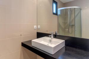 een badkamer met een witte wastafel en een spiegel bij Jardins do Oceano in Caniço