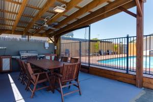 a patio with a table and chairs and a swimming pool at Wynnum Anchor Motel in Brisbane