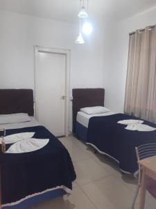 una habitación con 2 camas y una mesa y una mesa con mesa y mesa de mesa en Hotel Dal Gobo, en Ponta Grossa