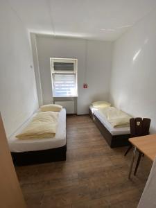 - 2 lits dans une chambre avec une table et une fenêtre dans l'établissement Budget Hotel Mannheim, à Mannheim