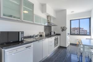 een keuken met witte kasten, een wastafel en een tafel bij Jardins do Oceano in Caniço