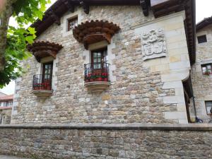 a stone building with two windows and flowers on it at Apartamentos Villa Julieta in Ruente