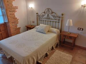 - une chambre avec un lit avec un couvre-lit blanc et 2 tables dans l'établissement EL PALACIO, à Ruente