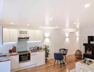 a kitchen with white cabinets and a blue chair at Majord'Home Spa 5* - La Source Cœur Vieille Ville in Annecy