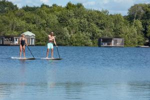 2 personnes sont debout sur des planches de paddle dans l'eau dans l'établissement Brindos, Lac & Château - Relais & Châteaux - Anglet Biarritz, à Anglet