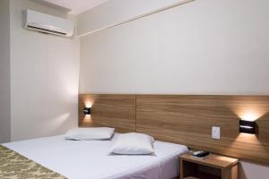 a bedroom with a white bed with a wooden headboard at Hotel Malibu Inn Campinas in Campinas