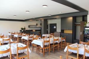 une salle à manger avec des tables et des chaises blanches dans l'établissement Hotel Posta, à Le Prese, Poschiavo