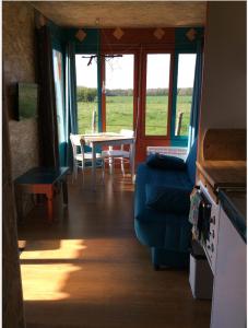 a living room with a table and a blue couch at Tiny House aux Chevaux du Perche 