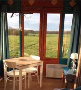 a table and chairs in a room with a window at Tiny House aux Chevaux du Perche 