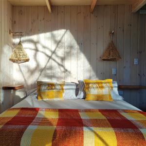 a bedroom with a bed with a colorful blanket at Malalcahuello Eco Glamp in Malalcahuello